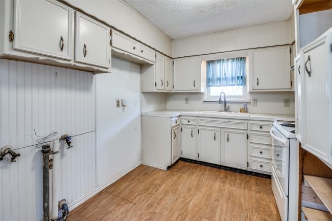 Kitchen with sink, white electric range oven, light hardwood / wood-style floors, a textured ceiling, and white cabinets | Image 13