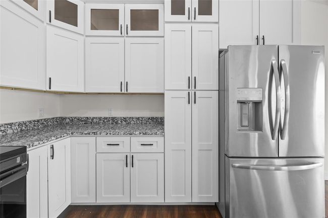Kitchen featuring stainless steel fridge, electric range oven, light stone countertops, and glass insert cabinets | Image 31