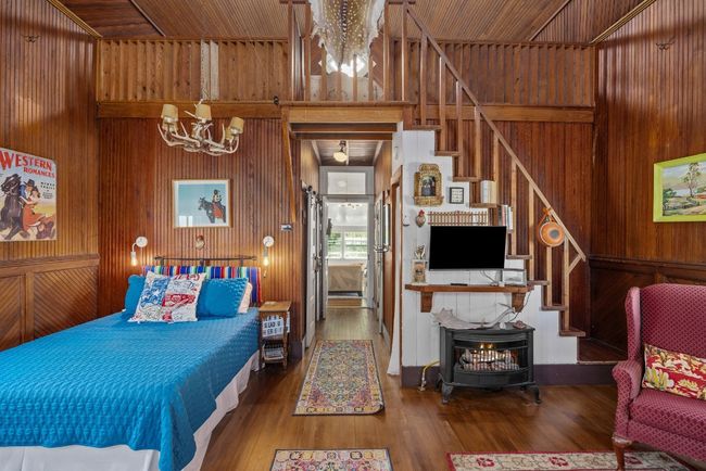 Bedroom featuring a chandelier, wood walls, a wood stove, and wood finished floors | Image 23