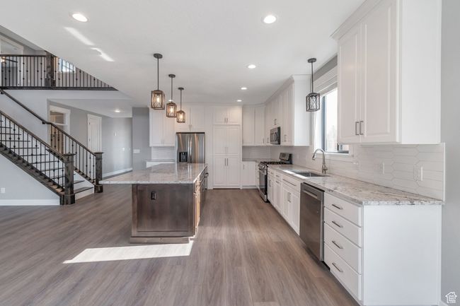 Kitchen featuring stainless steel appliances, wood finished floors, recessed lighting, tasteful backsplash, and a kitchen island | Image 13