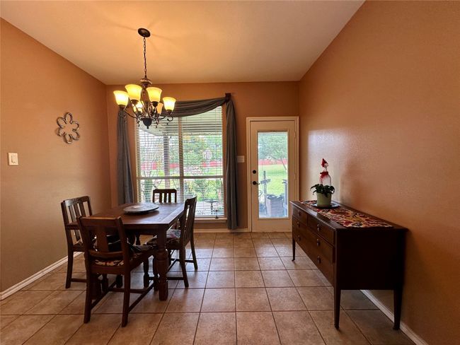 Dining space featuring light tile patterned flooring, baseboards, and a chandelier | Image 14