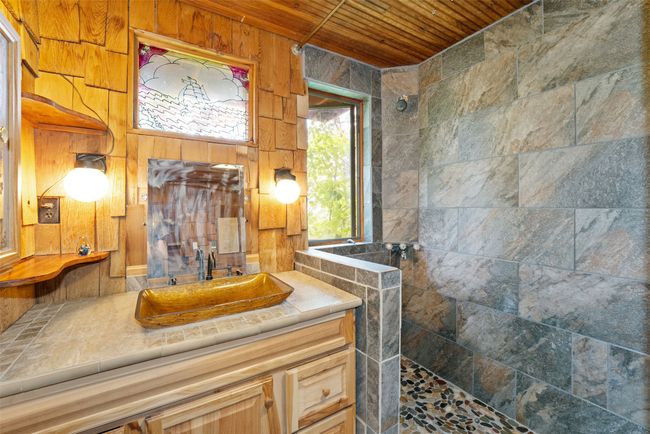 Bathroom featuring walk in shower, wood ceiling, vanity, and wood walls | Image 22