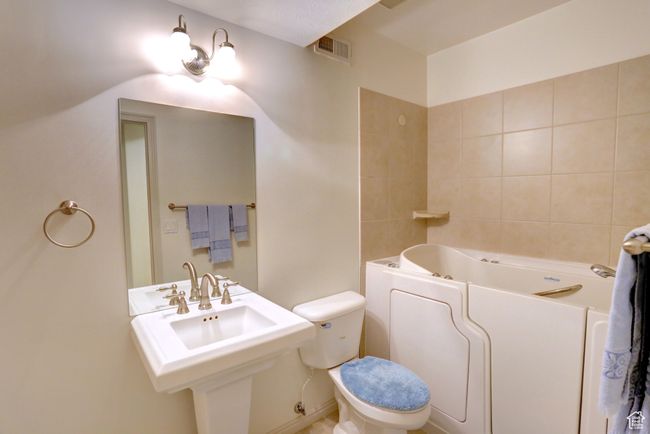 Bathroom with a sink, visible vents, toilet, and a bathtub | Image 44