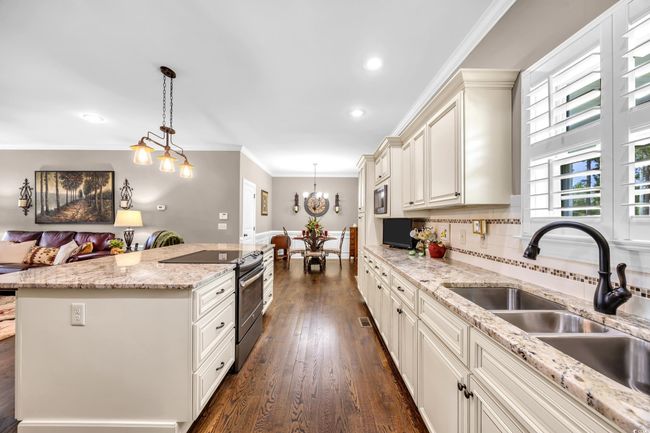 Kitchen featuring stainless steel range with electric stovetop, open floor plan, a sink, dark wood-style floors, and decorative light fixtures | Image 9