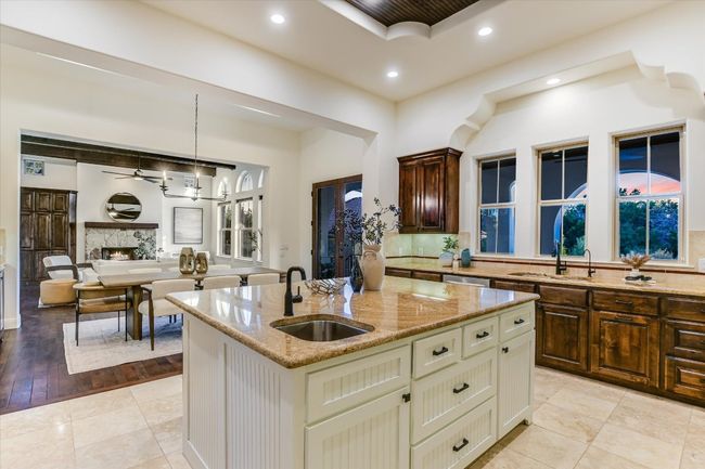 Kitchen featuring tasteful travertine backsplash, a sink, light stone countertops, recessed lighting, and a kitchen island with sink | Image 16