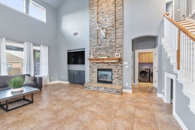 Huge masonry fireplace highlights the large living area with soaring ceilings, tile floors, overlooking the pool/deck. | Image 5
