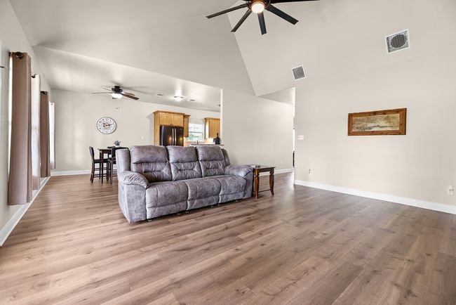 Living room with visible vents, ceiling fan, high vaulted ceiling, and light wood-style floors | Image 27