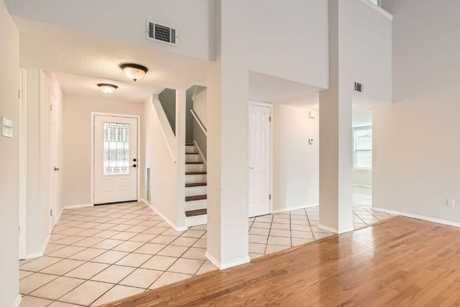 Foyer entrance featuring stairs, a high ceiling, visible vents, and light wood-type flooring | Image 4