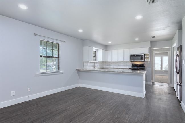 Kitchen featuring baseboards, a healthy amount of sunlight, stainless steel appliances, and dark wood-type flooring | Image 7