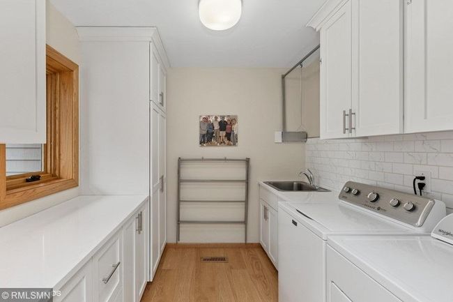 Amazing laundry room right off the kitchen! Plenty of cabinets and a great folding counter and drying bar! | Image 23