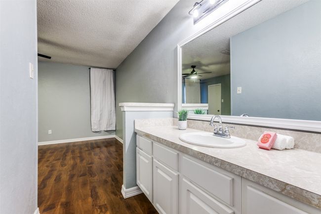 Bathroom with a textured ceiling, vanity, wood finished floors, and ceiling fan | Image 22