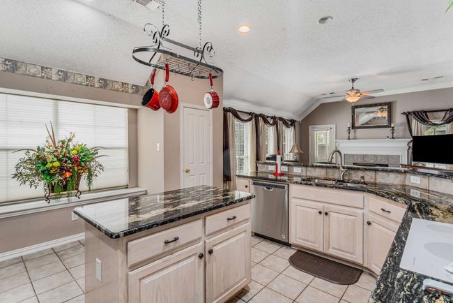 Kitchen with stainless steel dishwasher, pot rack, light tile patterned flooring, and vaulted ceiling | Image 14