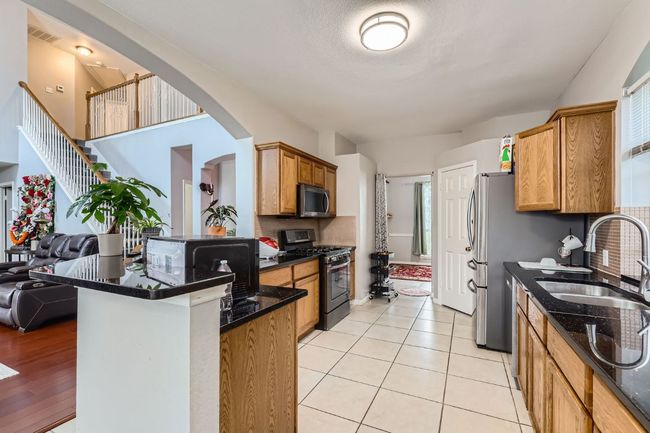 Kitchen with appliances with stainless steel finishes, a peninsula, arched walkways, decorative backsplash, and dark stone countertops | Image 9