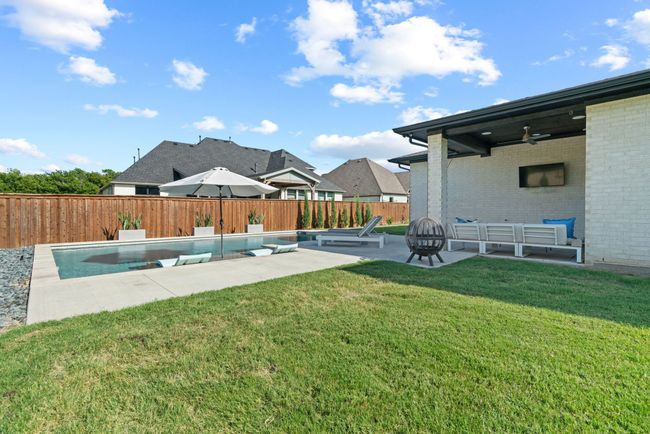 Fenced backyard with a ceiling fan, a patio area, an outdoor living space with a fire pit, and a residential view | Image 38