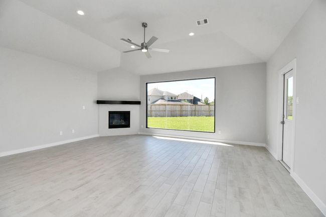 Family room flooded with natural light through the expansive window. The premium tile flooring adds a touch of luxury to the space, creating the perfect setting for relaxing moments and cherished gatherings with loved ones | Image 20