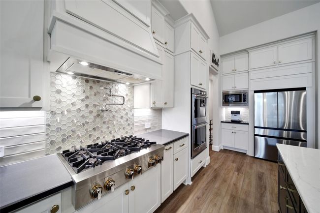 True chef’s kitchen featuring a professional-grade gas cooktop and convenient pot filler. | Image 12