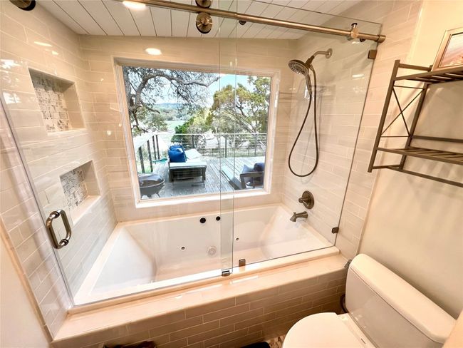 Indulge in serene lake views from the comfort of your luxurious primary bath/shower combo. | Image 12