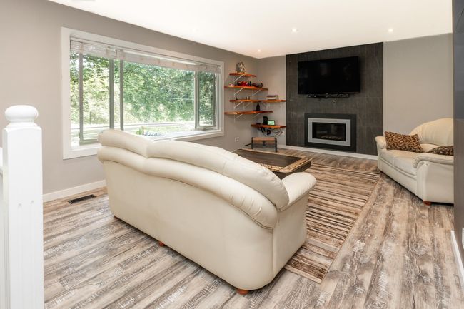 Living room featuring wood finished floors, healthy amount of natural light, a fireplace, baseboards, and recessed lighting | Image 5