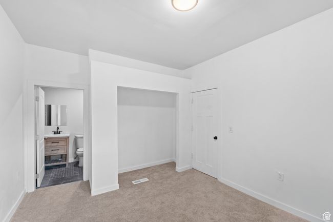 Unfurnished bedroom with carpet flooring, baseboards, a sink, connected bathroom, and visible vents | Image 11