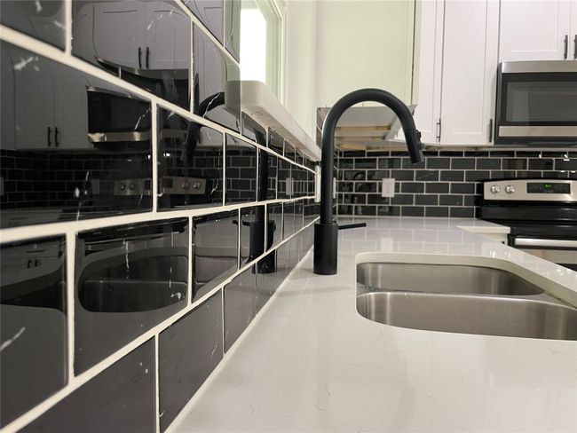 Kitchen featuring stainless steel appliances, decorative backsplash, light stone countertops, and white cabinets | Image 17