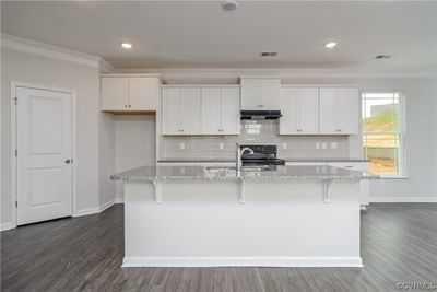 Photo represents the plan, not the actual home. Design selections may vary. Kitchen with quartz countertops, gas cooking, island, walk-in pantry, tile backsplash, stainless steel appliances and LED recessed lighting. | Image 3