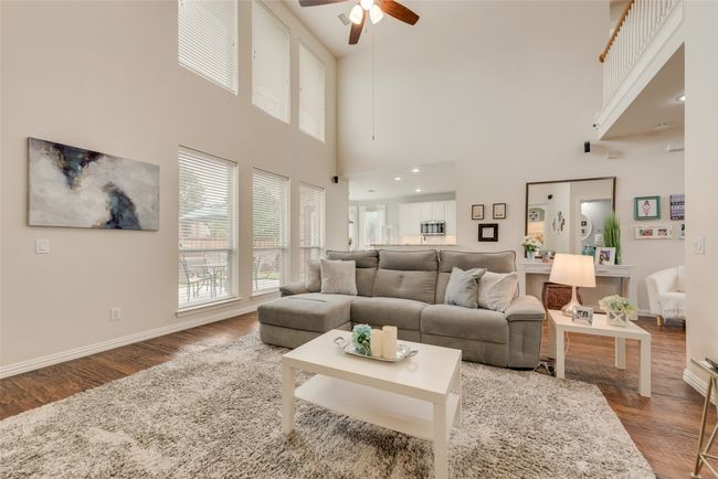 Living room with wood finished floors, a ceiling fan, baseboards, and a towering ceiling | Image 11