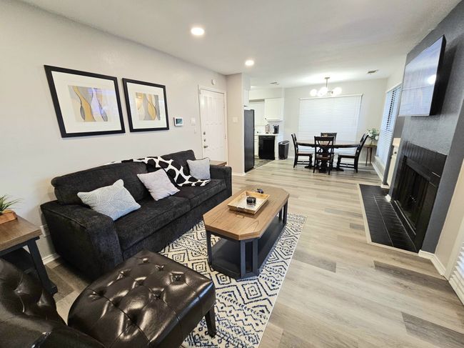 Living room with a chandelier, light wood-style floors, recessed lighting, baseboards, and a brick fireplace | Image 6