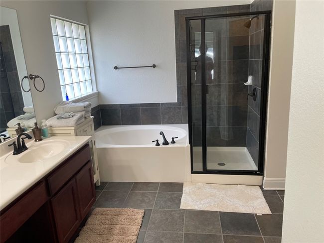 Full bath featuring vanity, a stall shower, a garden tub, and tile patterned floors | Image 18