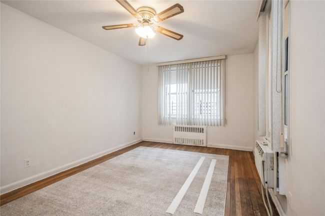 Spare room with radiator, dark wood-type flooring, and ceiling fan | Image 9