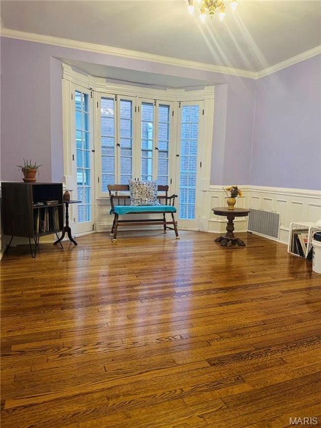 Living area with ornamental molding, hardwood / wood-style floors, a decorative wall, a wainscoted wall, and a chandelier | Image 6