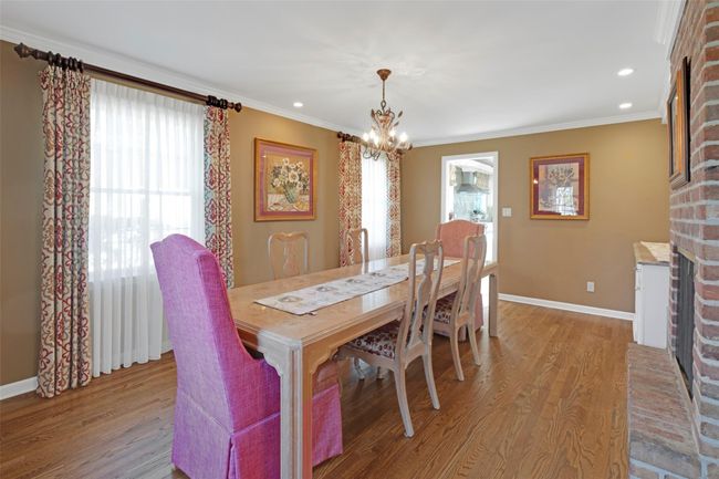 Dining space with light wood finished floors, plenty of natural light, a notable chandelier, and a fireplace | Image 6