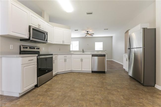Kitchen with appliances with stainless steel finishes, a peninsula, ceiling fan, and white cabinetry | Image 15