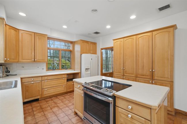 Kitchen with stainless steel electric stove, light brown cabinetry, visible vents, white refrigerator with ice dispenser, and light countertops | Image 15