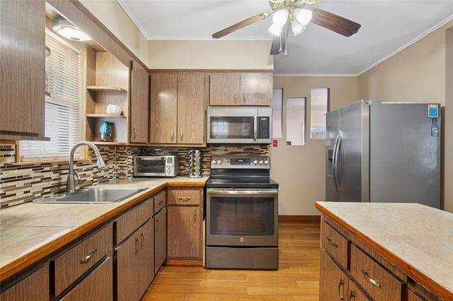 Kitchen featuring a sink, ceiling fan, appliances with stainless steel finishes, and crown molding | Image 7