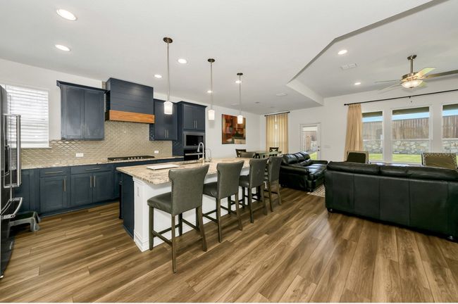 Kitchen featuring open floor plan, custom exhaust hood, a kitchen breakfast bar, and wood finished floors | Image 8