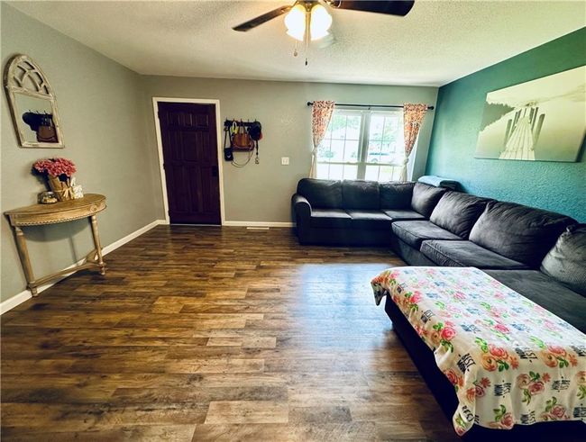 Living area featuring wood finished floors, a textured ceiling, a ceiling fan, and baseboards | Image 7
