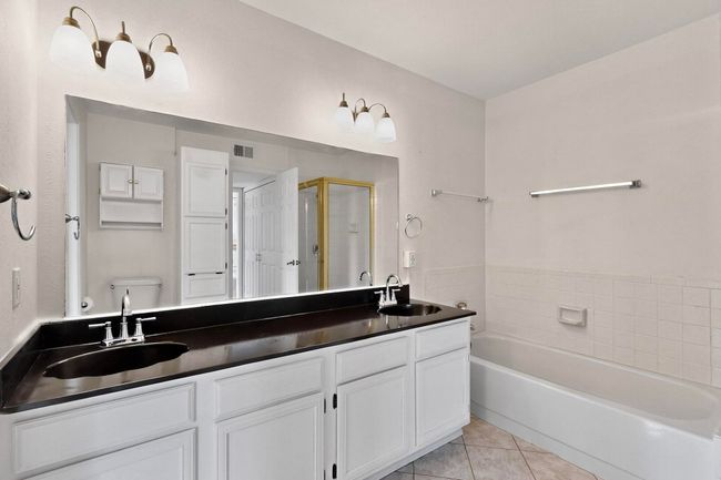 Bathroom featuring a bath, tile patterned floors, double vanity, a shower stall, and toilet | Image 24