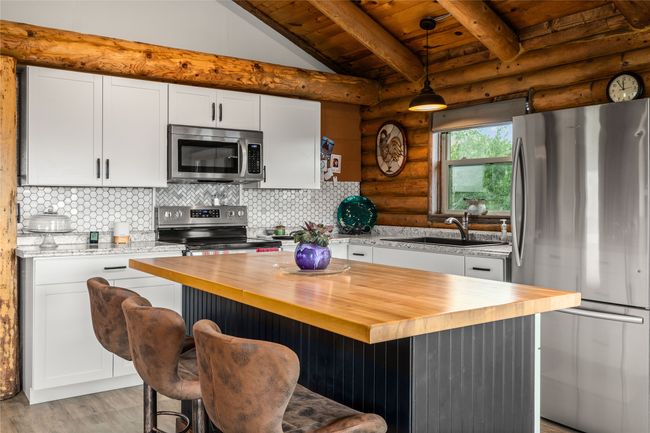 Kitchen featuring appliances with stainless steel finishes, wooden counters, rustic walls, white cabinets, and wooden ceiling | Image 10