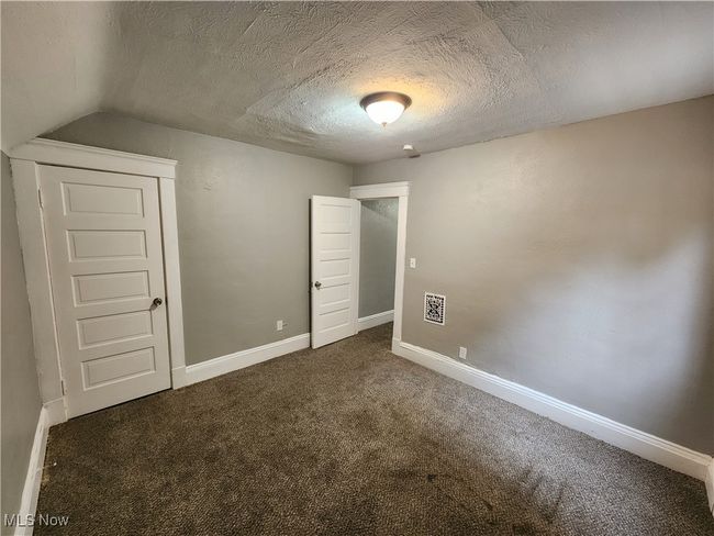 Unfurnished bedroom featuring lofted ceiling, a textured ceiling, and dark carpet | Image 20