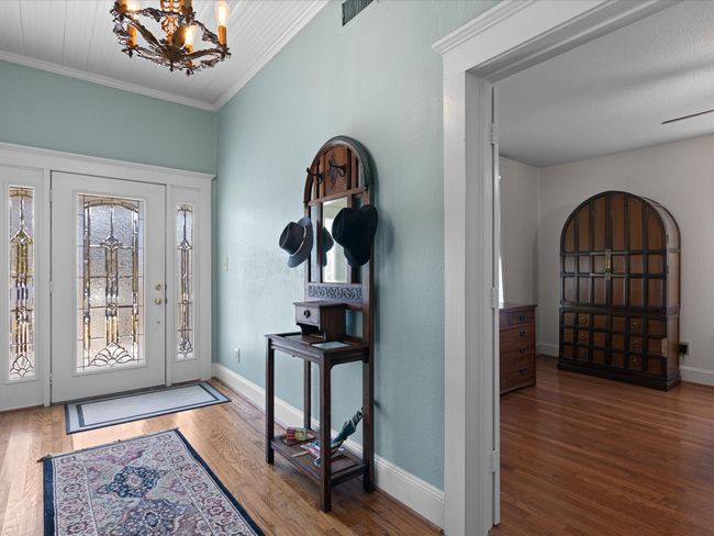 Entrance foyer with visible vents, crown molding, baseboards, a chandelier, and wood finished floors | Image 4