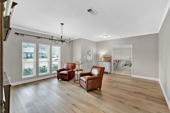 Sitting room featuring visible vents, crown molding, a chandelier, and light wood-type flooring | Image 6