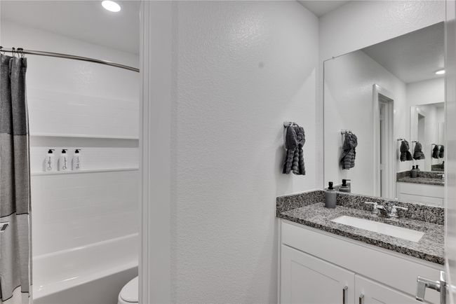 Bathroom featuring toilet, a textured wall, shower / washtub combination, and vanity | Image 30