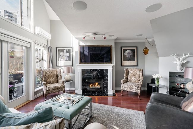 Living area with a high end fireplace, crown molding, baseboards, wood finished floors, and a wall mounted AC | Image 12