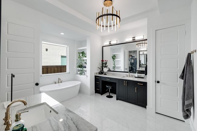 Bathroom featuring a chandelier, a soaking tub, vanity, marble finish flooring, and a shower | Image 21