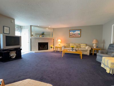 Living room featuring a textured ceiling, a tiled fireplace, and carpet | Image 2