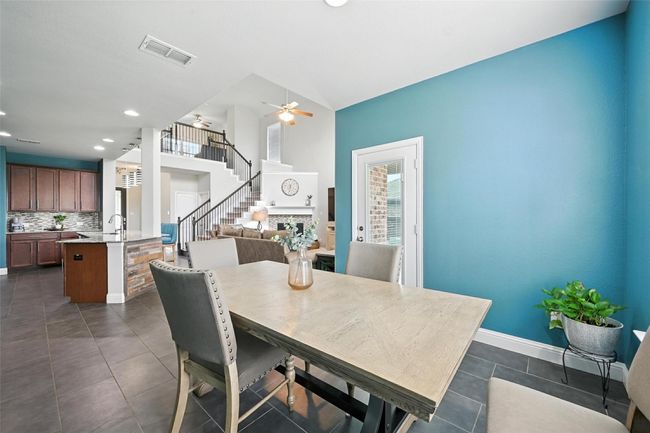 Dining area with stairs, dark tile patterned flooring, ceiling fan, and recessed lighting | Image 14