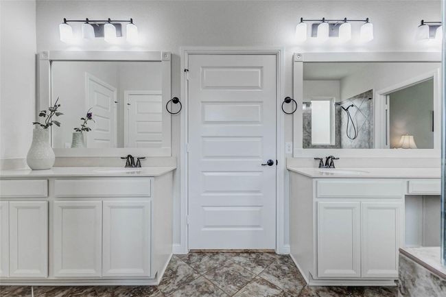 Additional features of the vanities include crisp white cabinetry and countertops, framed mirrors, and eye-catching bronze fixtures that add a touch of elegance. Between the vanities, you will find a door that leads to your massive walk in closet. | Image 18