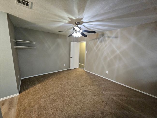 Unfurnished bedroom featuring carpet flooring, a textured ceiling, visible vents, baseboards, and ceiling fan | Image 22