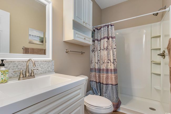 Bathroom featuring decorative backsplash, toilet, walk in shower, and vanity | Image 12