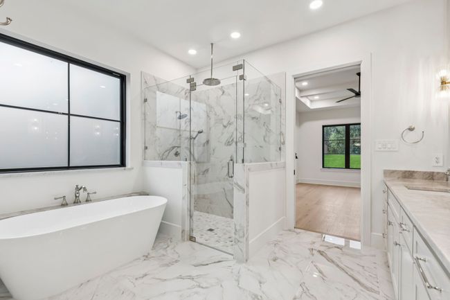 Full bathroom featuring a marble finish shower, vanity, a soaking tub, light marble finish floors, and ceiling fan | Image 22